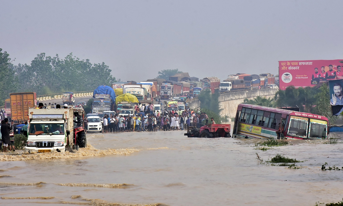 Commuters stand on a flyover on a flooded national highway after the Kosi river overflowed following heavy rain near Rampur in India's Uttar Pradesh state, on Wednesday, as the death toll from days of flooding and landslides in India surpassed at least 40. Photo: AFP