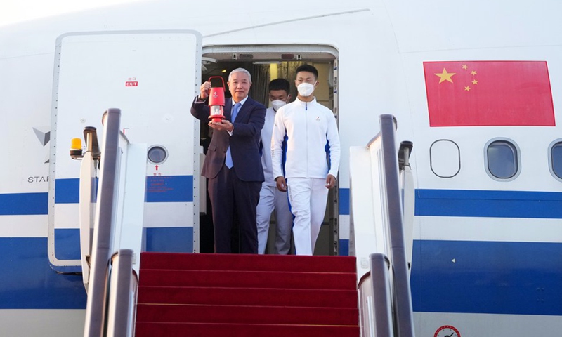 Special representative and vice president of Beijing 2022 Yu Zaiqing (L) holds up a lantern containing the Olympic flame as he walks out of the cabin at the Beijing Capital International Airport on Oct. 20, 2021.(Photo: Xinhua)