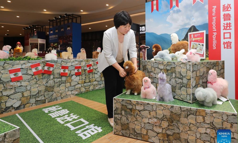 Ma Yuxia organizes alpaca-fur stuffed toys at the Peru Import Pavillon of the Greenland Global Commodity Trading Hub in Shanghai, east China, Oct. 15, 2021. Photo: Xinhua
