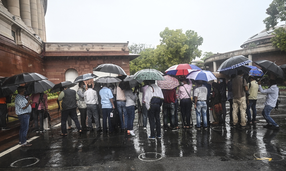 Media representatives hold umbrellas during a rainfall as they wait for the Indian Prime Minister Narendra Modi in New Delhi on July 19, 2021. Photo: AFP