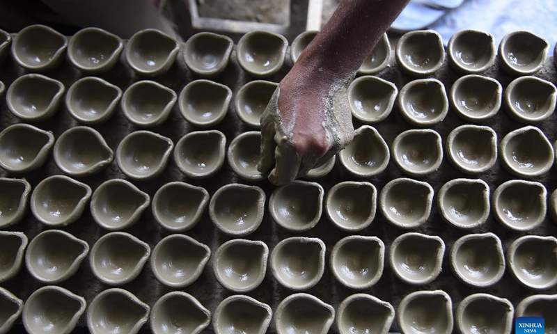 A potter arranges earthen lamps made for Diwali, the Hindu Festival of Lights, in Nagaon district of India's northeastern state of Assam, Oct. 21, 2021. Photo: CFP