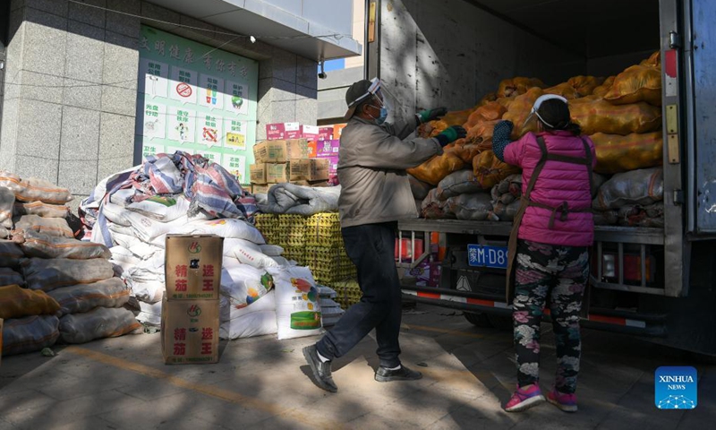 Staff members carry bags of daily necessities outside a supermarket in Ejina Banner of Alxa League, north China's Inner Mongolia Autonomous Region, Oct. 20, 2021.Photo: Xinhua