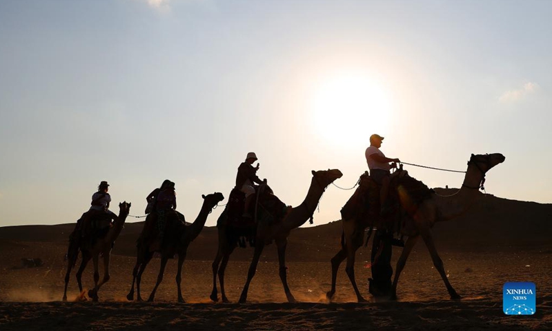 Tourists ride camels to view the Giza Pyramids in Giza, Egypt, on Oct. 21, 2021.Photo:Xinhua