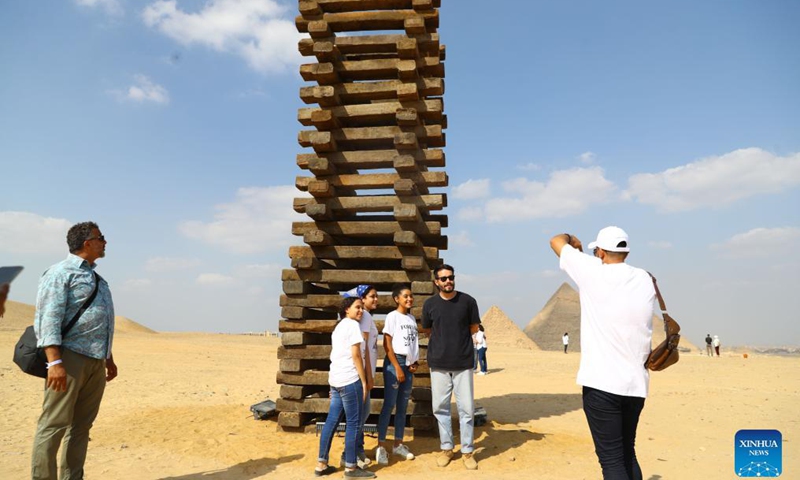 Visitors pose for photos with an artwork during an international art exhibition in Giza, Egypt, on Oct. 21, 2021. Egypt launched on Thursday the first international art exhibition at the Great Pyramids of Giza and their surrounding plateau with the participation of artists from Egypt and other countries.Photo:Xinhua