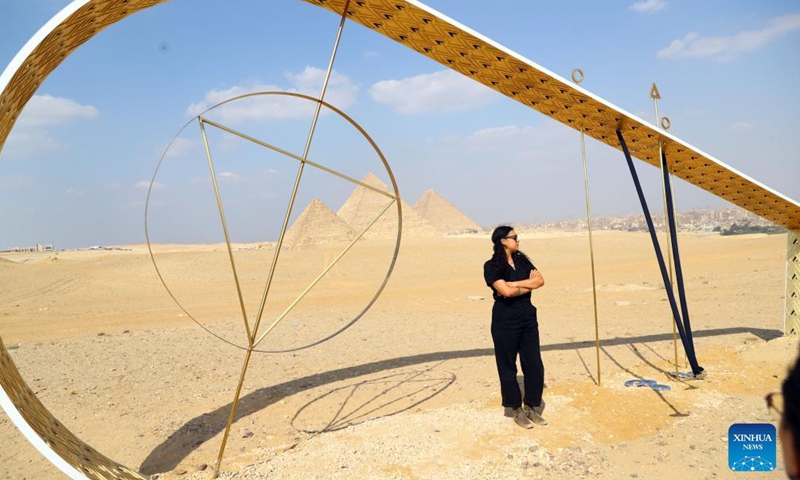 A visitor poses for a photo with an artwork during an international art exhibition in Giza, Egypt, on Oct. 21, 2021. Egypt launched on Thursday the first international art exhibition at the Great Pyramids of Giza and their surrounding plateau with the participation of artists from Egypt and other countries.Photo:Xinhua