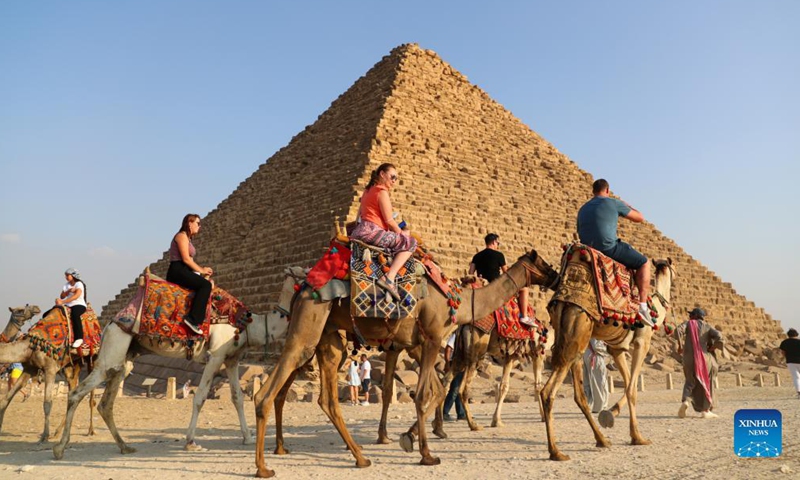 Tourists ride camels to view the Giza Pyramids in Giza, Egypt, on Oct. 21, 2021. Egypt has entered peak tourist season as the weather is becoming cooler, and international flights to the country suspended due to COVID-19 are gradually resuming. The Giza Pyramids scenic spot is being visited by more and more tourists.Photo:Xinhua