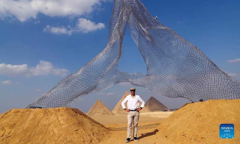 Italian artist Lorenzo Quinn poses for a photo with his sculpture Together during an international art exhibition in Giza, Egypt, on Oct. 21, 2021. Egypt launched on Thursday the first international art exhibition at the Great Pyramids of Giza and their surrounding plateau with the participation of artists from Egypt and other countries.Photo:Xinhua