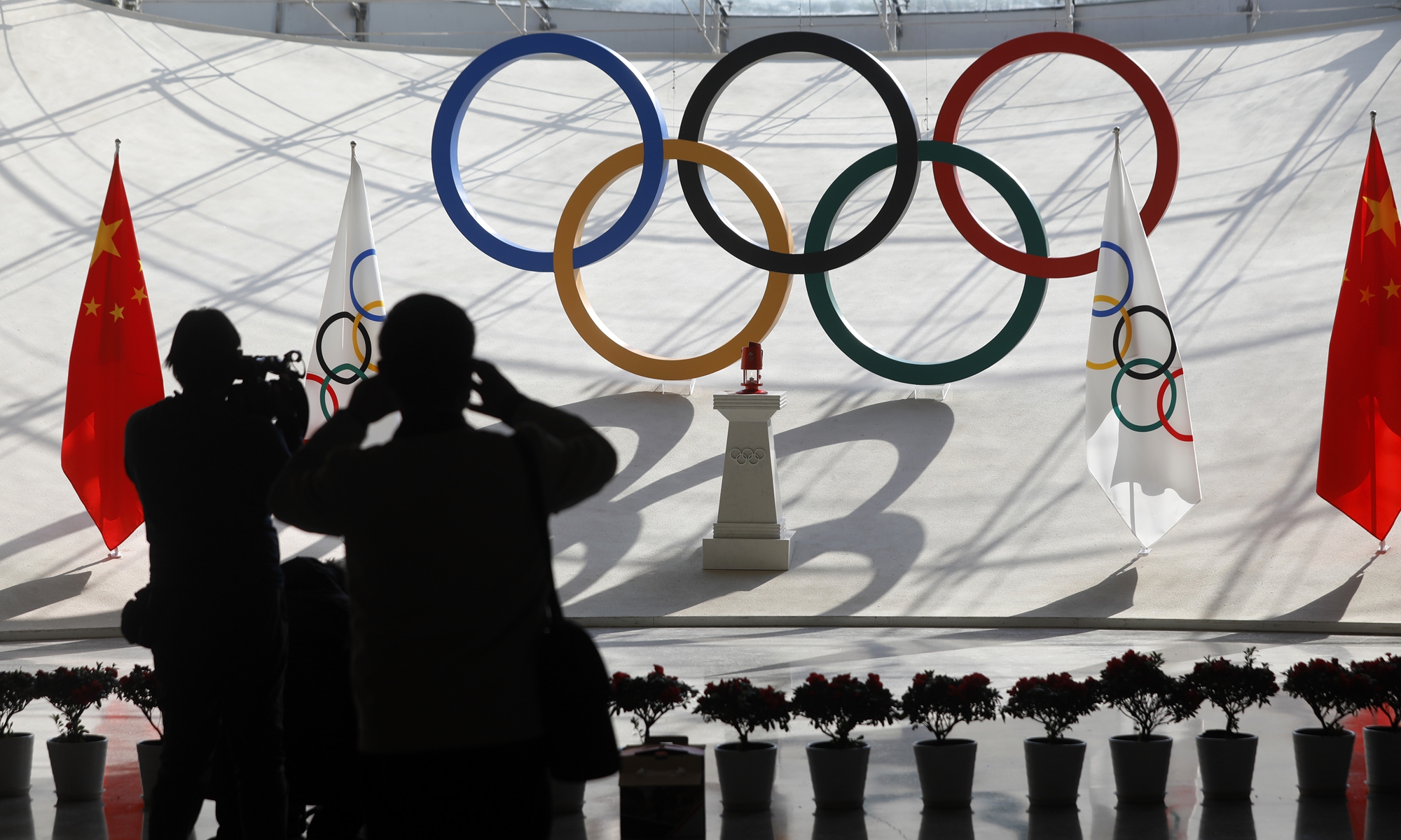 Visitors take pictures of the flame of the Beijing 2022 Winter Olympic Games displayed at the Olympic Tower near the 