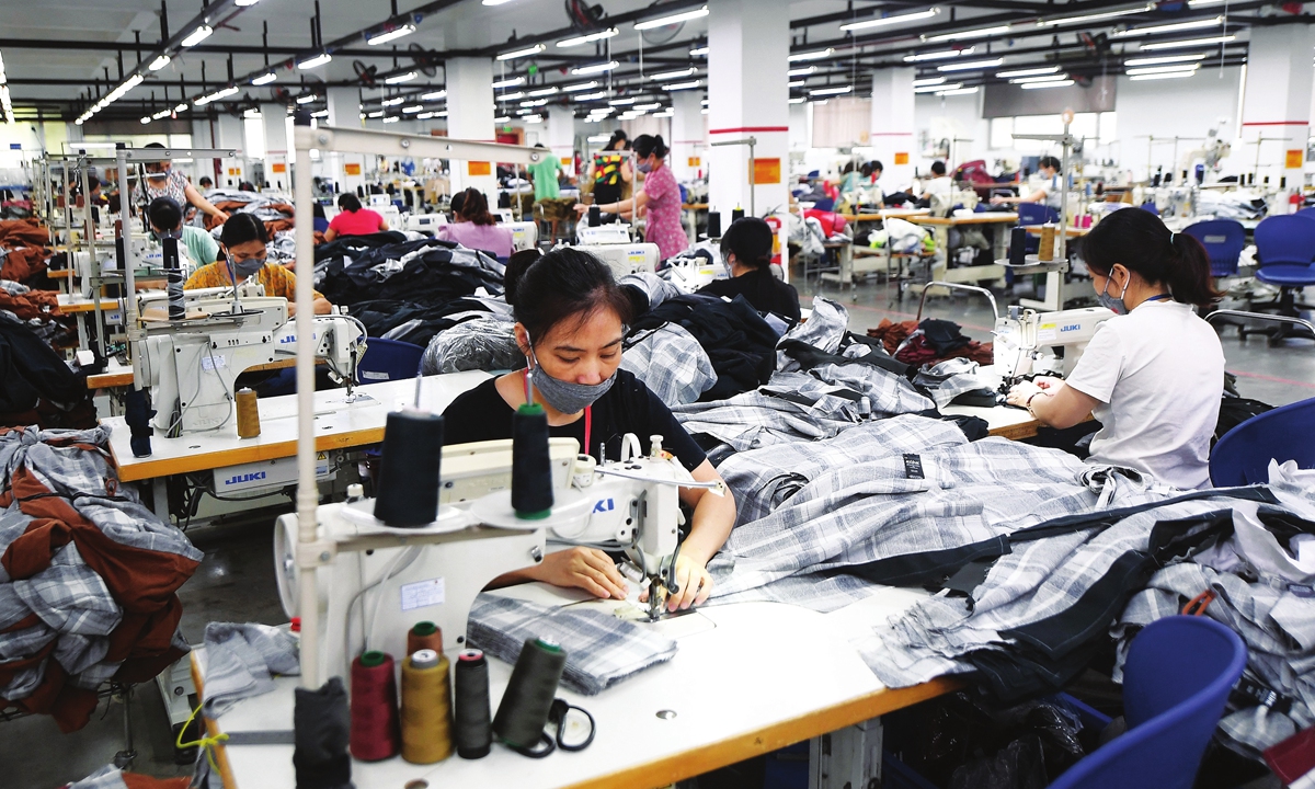 Workers wearing face masks make activewear for various textile clothing brands at a factory in Hanoi on September 21, 2021. Photo: AFP