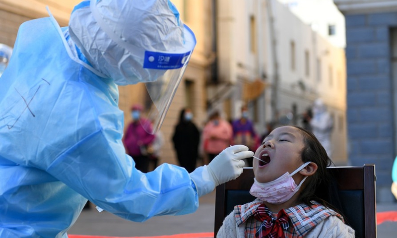 A medical worker takes a swab sample from a child for nucleic acid test at a residential area in Ejin Banner of Alxa League, north China's Inner Mongolia Autonomous Region, Oct. 20, 2021.Photo: Xinhua
