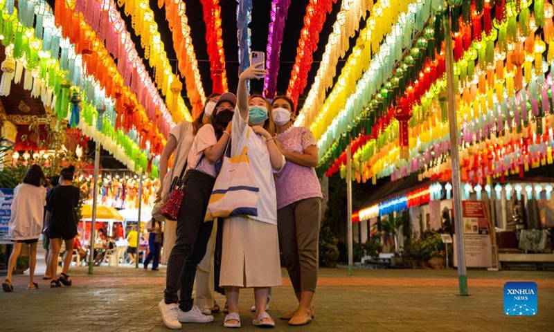 Tourists take a selfie at Wat Phra That Haripunchai in Lamphun, Thailand on October 25, 2021.  Thailand's Lamphun province held a grand lantern festival at Wat Phra That Haripunchai, attracting tourists to hang lanterns and greet.  Photo: Xinhua