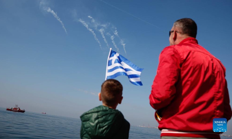 A boy with a Greek flag watches a military aircraft during a military parade in Thessaloniki, northern Greece, on Oct. 28, 2021. Amid COVID-19 restrictions especially in the northern part of the country, Greece celebrated the annual Ochi (No) Day on Thursday with military and student parades.Photo:Xinhua