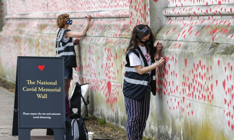 Volunteers paint red hearts representing the victims who died of COVID-19 on the National COVID Memorial Wall outside St Thomas' Hospital in London, Britain, on March 31, 2021.(Photo: Xinhua)
