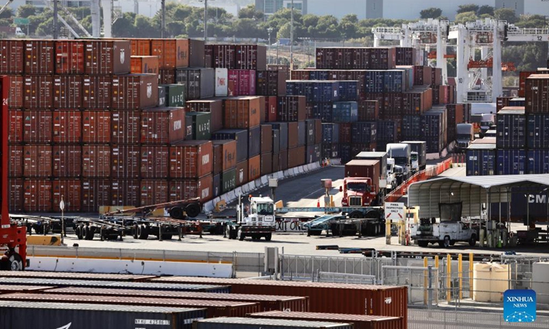 Trucks are seen by the piled-up containers at the port of Los Angeles, California, the United States, Oct. 29, 2021.Photo:Xinhua