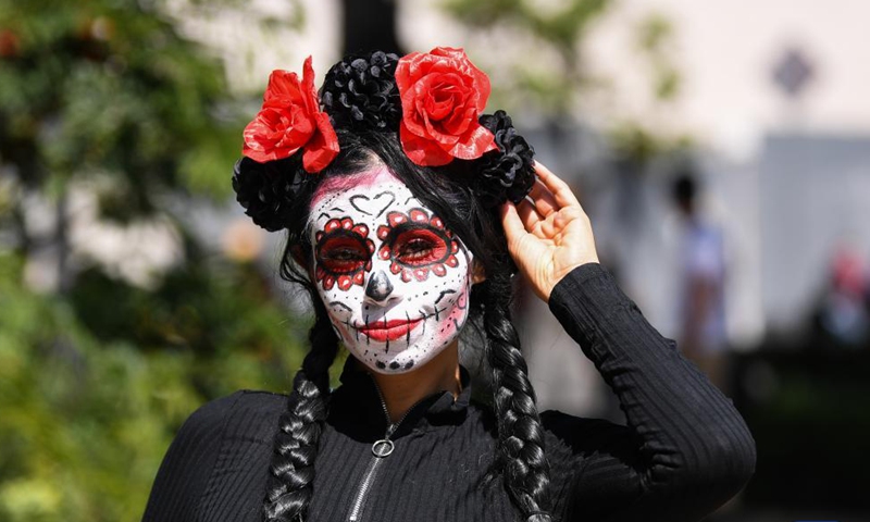 A woman in ghostly makeup and costumes poses for a photo when taking part in the Day of the Dead Parade in downtown Mexico City, capital of Mexico, on Oct. 31, 2021.Photo:Xinhua