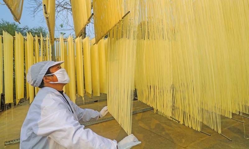 A villager makes dried noodles in Guangshan county, Central China's Henan Province on November 1, 2021. Local farmers have standardized their manufacturing procedures, packaging and trademarks, and they're taking advantage of e-commerce platforms to ship noodles across the country. Photo: cnsphoto 