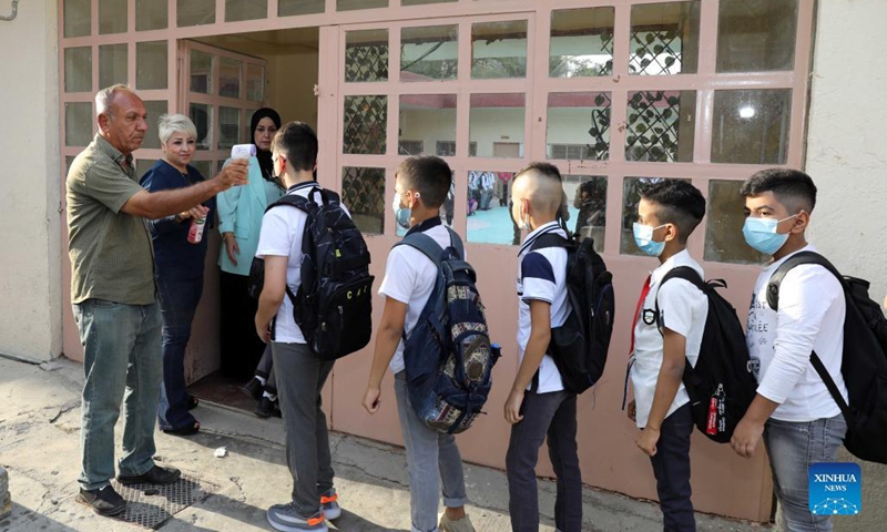 Students have their temperature checked before they enter school on the first day of the new school year in Baghdad, Iraq, Nov. 1, 2021.(Photo: Xinhua)