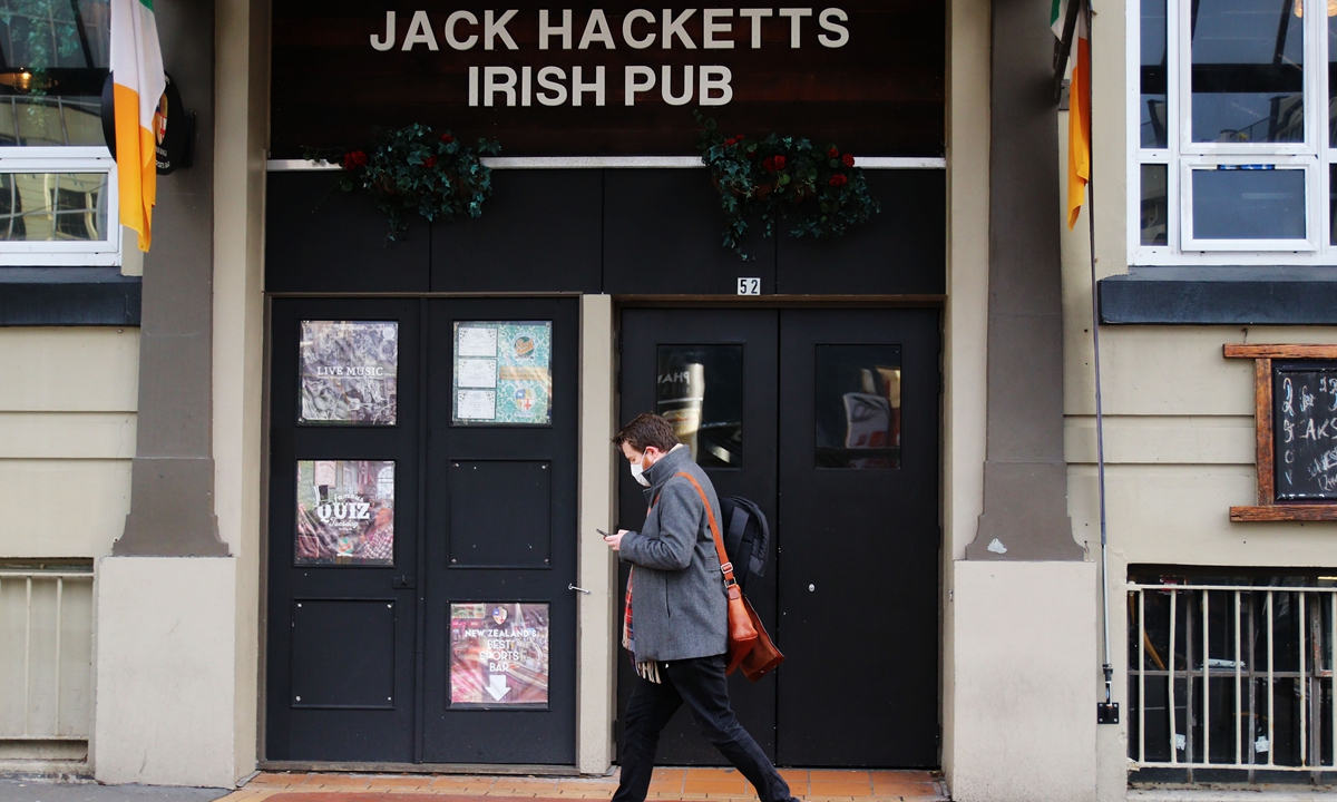 A man in a medical face mask walks past the Jack Hacketts Irish Pub on June 23 in Wellington, New Zealand. Photo: VCG