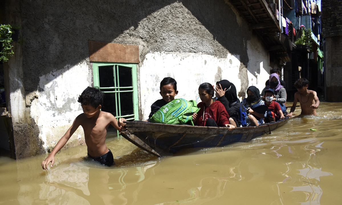 A family evacuate from their flooded home following heavy rain in Bandung, Indonesia on Wednesday. Four people have lost their lives due to the landslides and floods in the country by Wednesday. Photo: AFP
