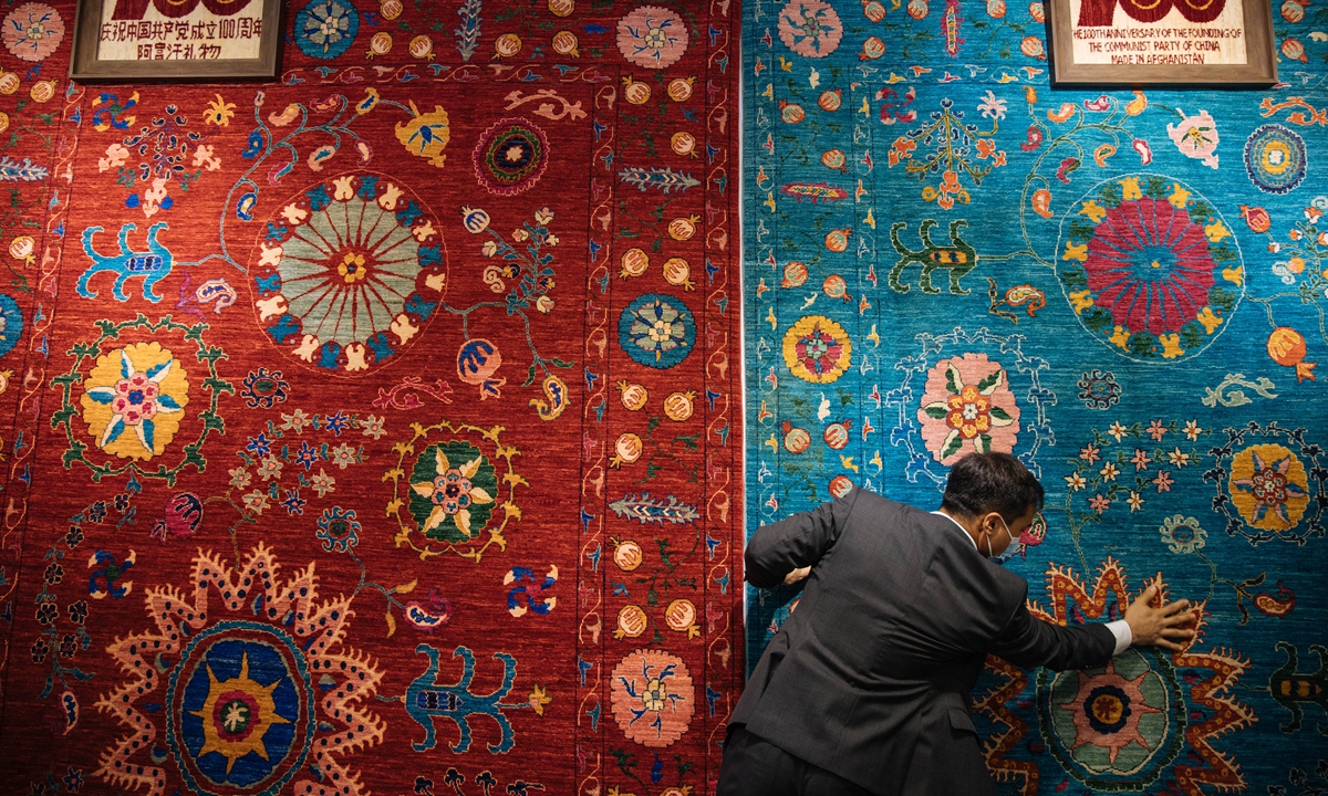 Ali Faiz, an Afghan handmade carpet exhibitor at CIIE, shows the carpets to the reporter. Photo: Li Hao/GT