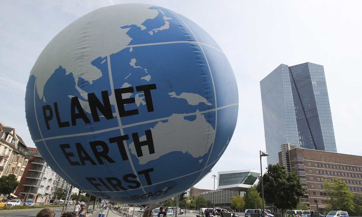 Climate activists walk with a balloon featuring the Earth during a demonstration called by Fridays for Future, Greenpeace, KoalaKollektiv and others to protest against bank investments in fossil fuels on August 13 in Frankfurt, Germany. Photo: AFP