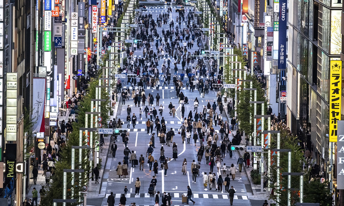 People walk on a street in Tokyo's Ginza area at dusk on Sunday. Japan reported about 230 new COVID-19 cases as of Sunday, bringing the total number of infections to about 1.72 million, with more than 18,000 deaths. Photo: AFP