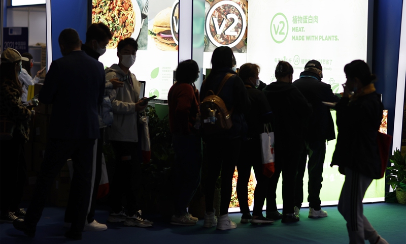 Visitors line up to taste vegetable protein meat at the food and agricultural products exhibition area at the 4th China International Import Expo in Shanghai on November 9, 2021. The expo is hosting the first gathering of the world's five largest grain merchants, which are displaying their technological innovations, including plant-based, organic, and functional food. Photo: VCG
