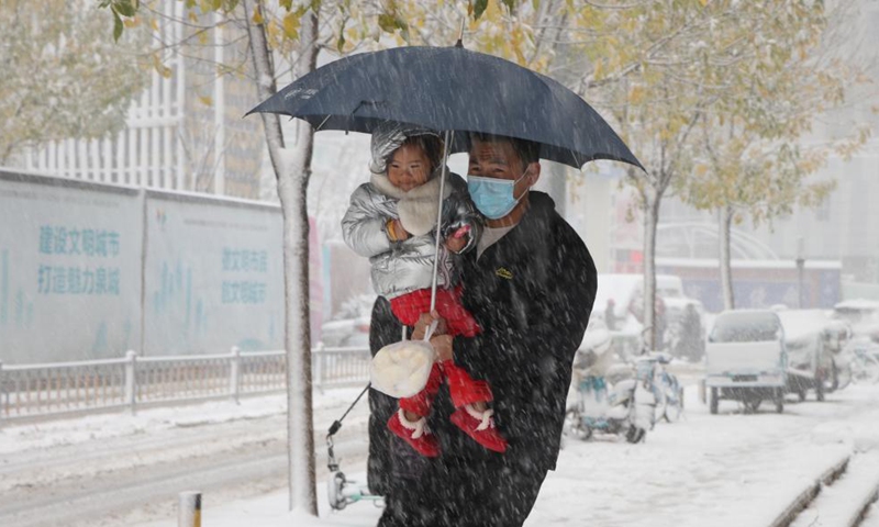 A citizen holding a kid walks amid snow in Jinan, capital of east China's Shandong Province, Nov. 7, 2021.Photo:Xinhua