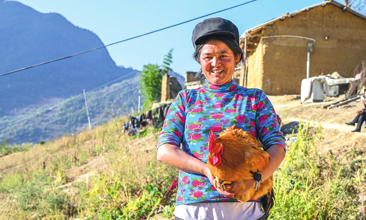 A woman from the cliff village in Sichuan Province shows off her rooster. Villagers now supplement their income by developing tourism. Photo: VCG 