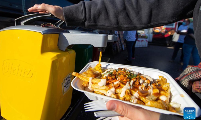 A customer puts some yellow mustard on her poutine at the Toronto Poutine Festival in Toronto, Canada, on Nov. 7, 2021.Photo:Xinhua