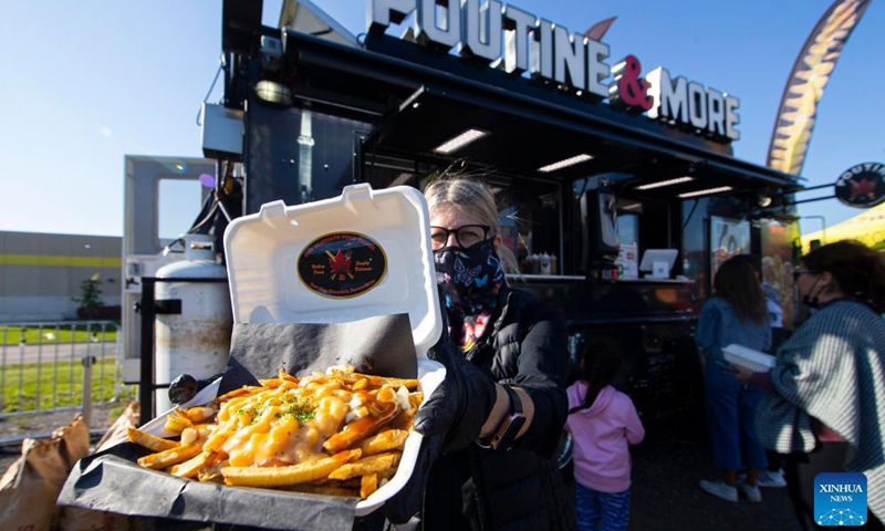 A vendor wearing a face mask displays a poutine in front of a food truck at the Toronto Poutine Festival in Toronto, Canada, on Nov. 7, 2021.Photo:Xinhua