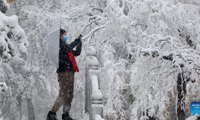 A citizen takes photos amid snow at Renmin Park in Liaocheng City, east China's Shandong Province, Nov. 7, 2021.Photo:Xinhua