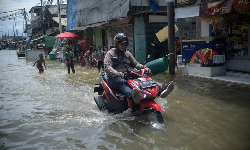 A man rides a motorcycle on a water-logged road on the coast of Jakarta, Indonesia, Nov. 9, 2021.(Photo: Xinhua)