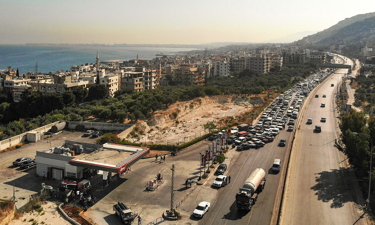 Vehicles on the left lane adjacent to a petrol station queue up for fuel as traffic flows through on the Tripoli-Beirut highway in Qalamun, northern Lebanon on July 1 amid severe fuel shortages. Photo: AFP