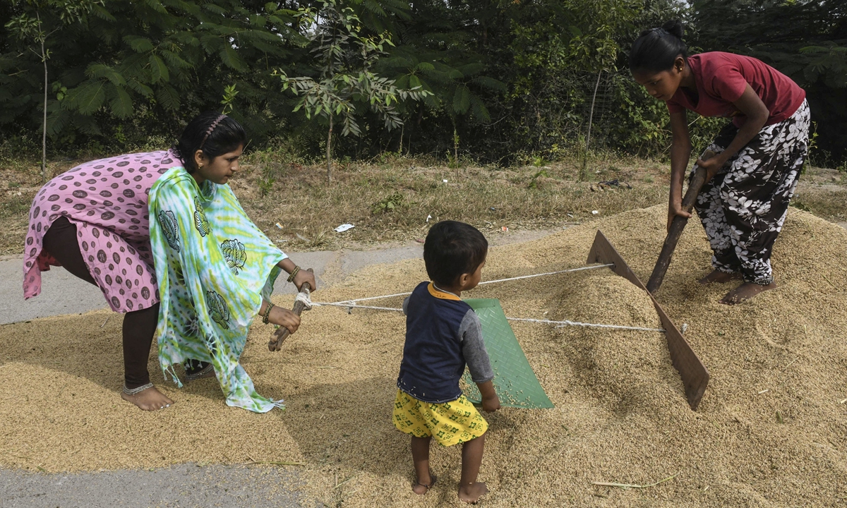 Farmers spread unpolished rice to dry along a highway in Toopran Mandal in the Medak district, some 55 kilometers from Hyderabad, India on Thursday. Photo: AFP