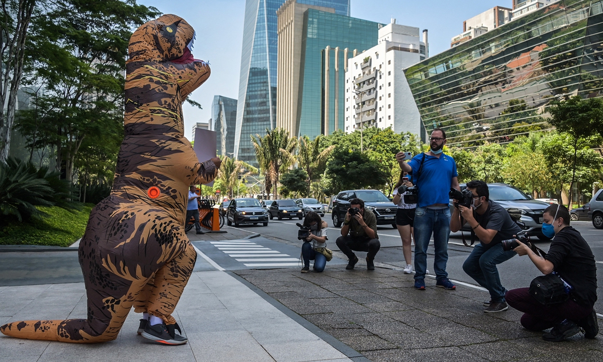 An environmental activist disguised as a dinosaur protests in front of BTG Pactual Bank headquarters in Sao Paulo, Brazil on November 5, denouncing Latin America's largest investment bank that supports the fossil fuel industry. Photo: AFP