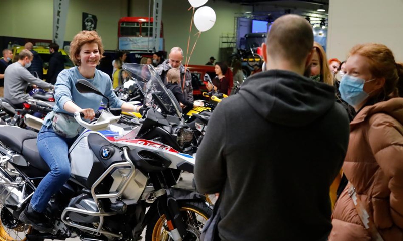 A woman poses for a photo on a motorcycle during a travel vehicles exhibition in Moscow, Russia, Nov. 14, 2021.Photo:Xinhua