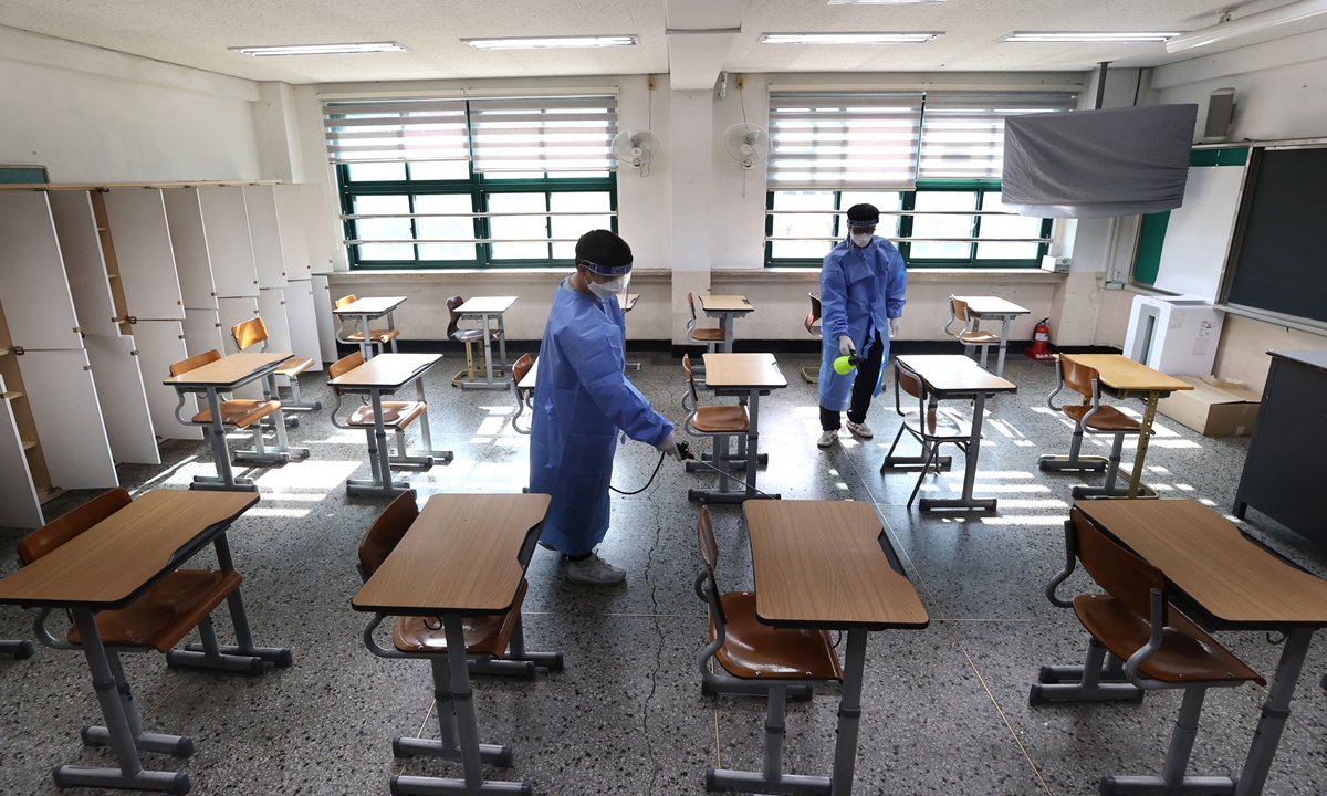Quarantine workers disinfect a classroom for the state-administrated college entrance test at Seokgwan High School in Seoul, South Korea on November 16, 2021, two days before the test to be taken by 509,821 students nationwide amid the pandemic, Yonhap News Agency said. Photo: VCG