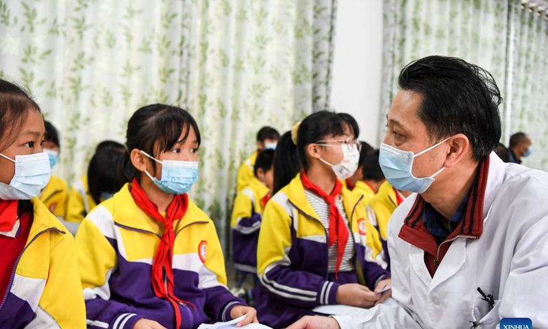 A medical worker explains after-vaccination instructions to pupils after they get inoculated with the COVID-19 vaccines at Weiming elementary school in Weiming Village, Shinan Township, Xingye County, south China's Guangxi Zhuang Autonomous Region, Nov. 18, 2021. Photo: Xinhua