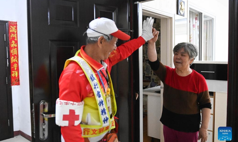 Octogenarian Ma Jinming says goodbye to his wife as he sets off to direct traffic voluntarily in Taiyuan, capital of north China's Shanxi Province, Nov. 17, 2021. Ma Jinming, 80, has kept up voluntarily directing traffic on the street for eleven years. Photo: Xinhua