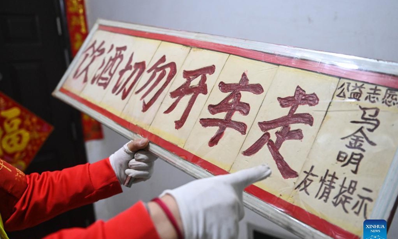 Octogenarian Ma Jinming shows the drunken-driving warning sign made by himself in Taiyuan, capital of north China's Shanxi Province, Nov. 17, 2021. Ma Jinming, 80, has kept up voluntarily directing traffic on the street for eleven years. Photo: Xinhua