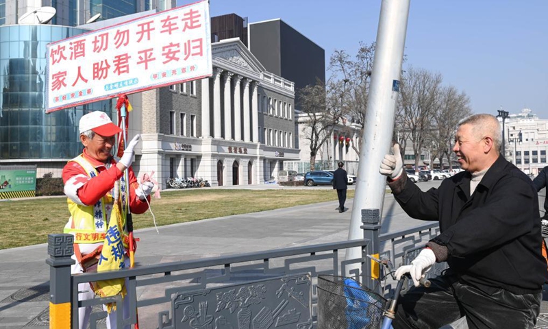 A citizen greets octogenarian Ma Jinming as he directs traffic voluntarily in Taiyuan, capital of north China's Shanxi Province, Nov. 17, 2021. Ma Jinming, 80, has kept up voluntarily directing traffic on the street for eleven years. Photo: Xinhua