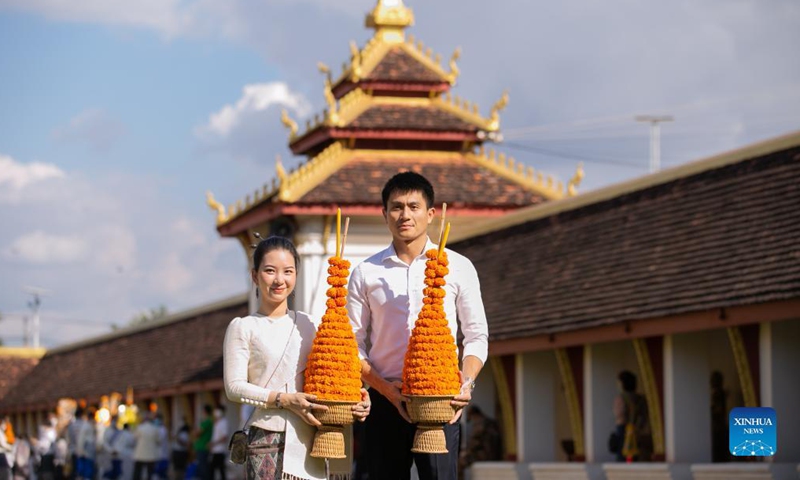 People pose for a photo at That Luang Stupa in Vientiane, Laos, Nov. 18, 2021. The That Luang Festival, the most important religious festival in Laos, was observed by Lao people from all over the country around the That Luang Stupa. (Photo by Kaikeo Saiyasane/Xinhua)