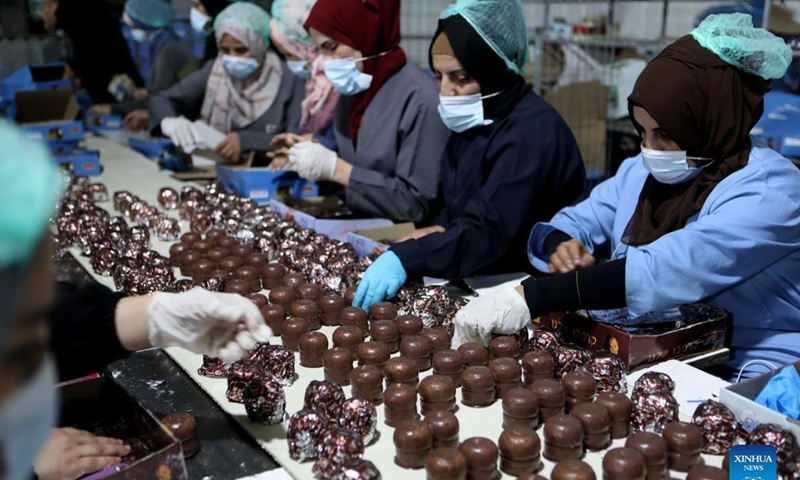 Palestinian workers wrap up chocolate Ras el-Abd at a sweet factory in the West Bank city of Hebron, Nov. 18, 2021. Ras el-Abd is a traditional candy covered with chocolate. (Photo by Mamoun Wazwaz/Xinhua) 
