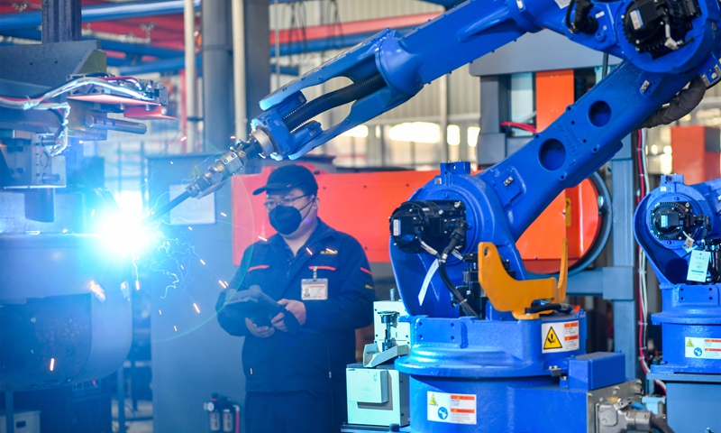 A worker controls an automated robot workstation operating at high speed in a digital workshop in Huzhou, East China's Zhejiang Province on November 30, 2021. The workshop has introduced intelligent production and assembly lines. High-tech products such as 5G unmanned forklift trucks and automated guided vehicles are mainly sold to countries and regions under the Belt and Road Initiative. Photo: VCG