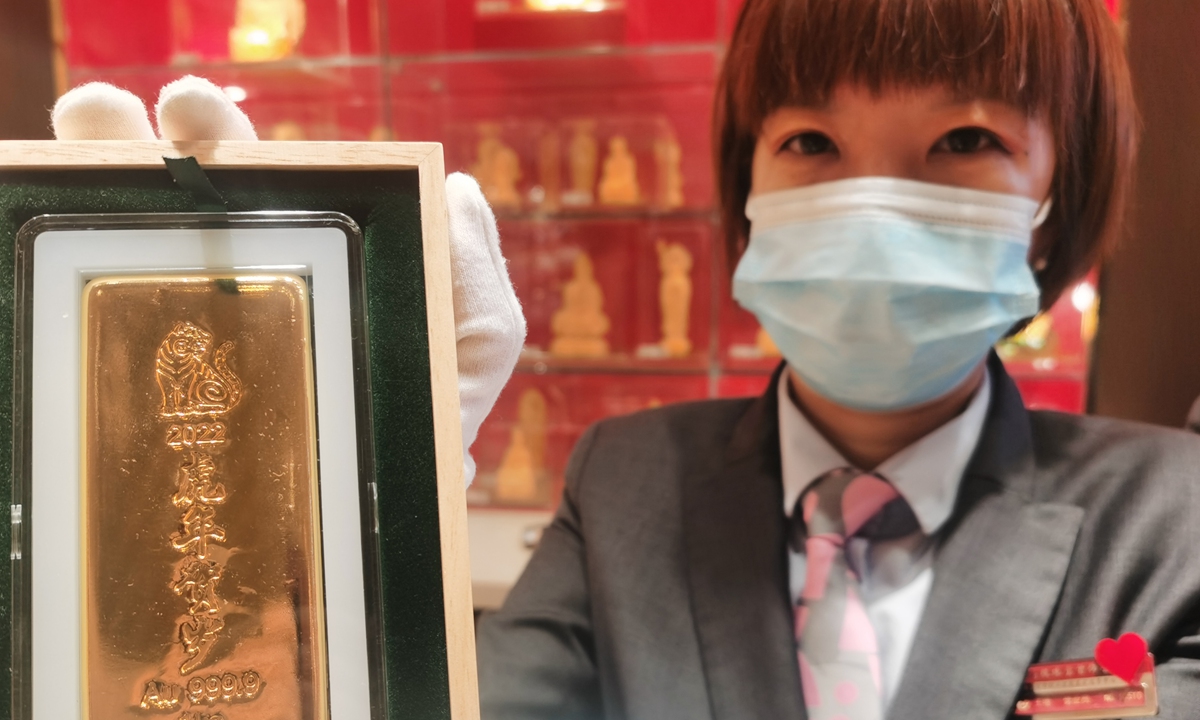 A salesperson shows a gold bar carved with the image of tiger at a department store in Beijing on November 22. The gold bar is being offered to celebrate the upcoming Chinese zodiac Year of the Tiger, and it signals good fortune. Photo: cnsphotos 