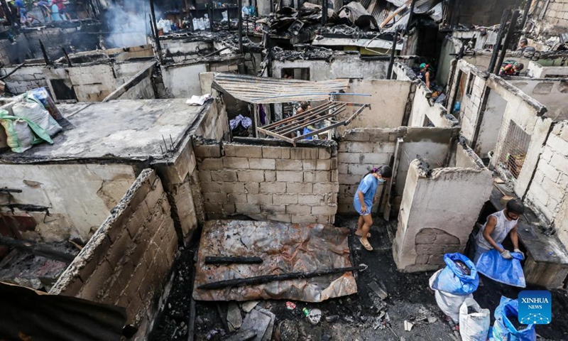 A man searches for belongings after a fire at a residential area in Quezon City, the Philippines, Nov. 23, 2021. The fire took place on Monday, leaving 120 shanties razed. Photo: Xinhua