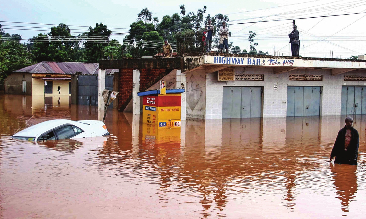 A Ugandan resident walks through the floods while others are marooned on rooftops following heavy rains on November 16, 2007 in Kampala, Uganda. Photo: AFP