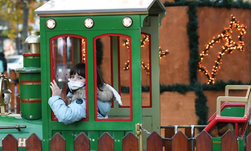 A girl with a face mask rides on a mini train at the Frankfurt Christmas Market in Frankfurt, Germany, Nov. 22, 2021.Photo:Xinhua