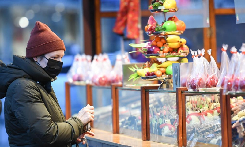 A woman with a face mask selects dessert at the Frankfurt Christmas Market in Frankfurt, Germany, Nov. 22, 2021.Photo:Xinhua